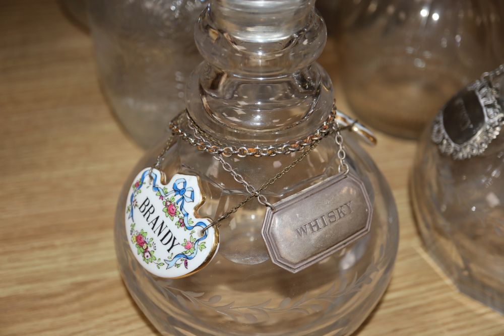 A pair of cut glass decanters, three other decanters, a claret jug and other glassware together with various labels, one silver whisky